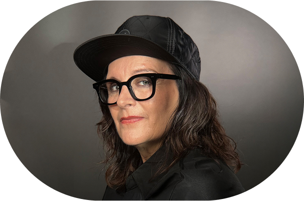 Bild von Anja Maria Welzel wie sie im Profil in die Kamera guckt. Sie trägt ein Cap und eine Brille.